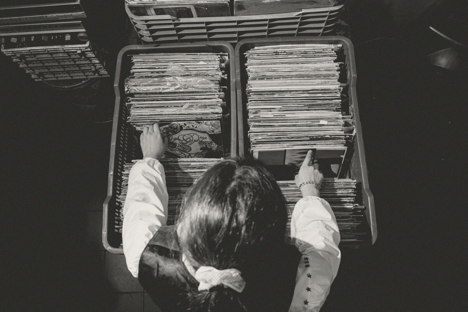 Seen from above, someone flipping through record sleeves in a crate.