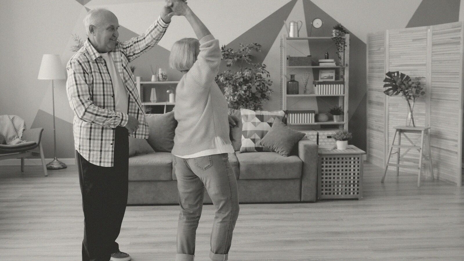 An older couple dancing together in their living room.