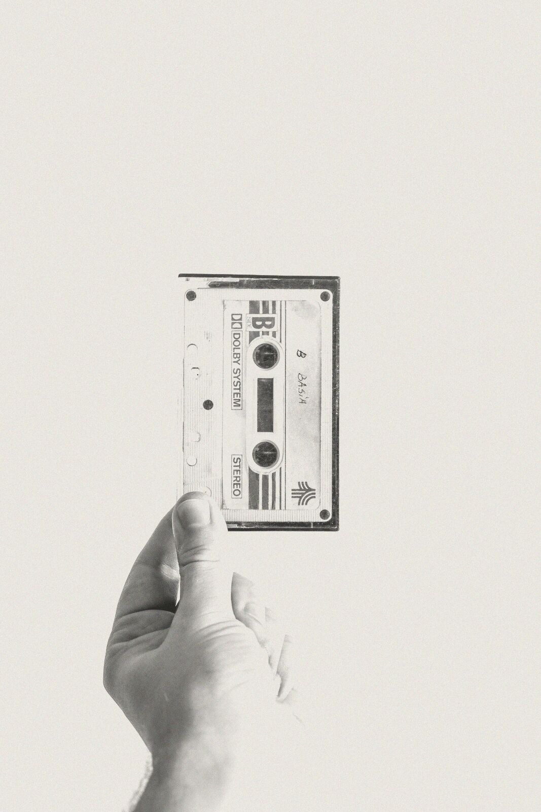 A hand holding out a cassette tape.